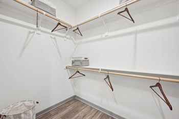 A white closet with hangers on the wall and a basket on the floor